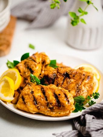 grilled greek marinated chicken breast on a white plate with styled background