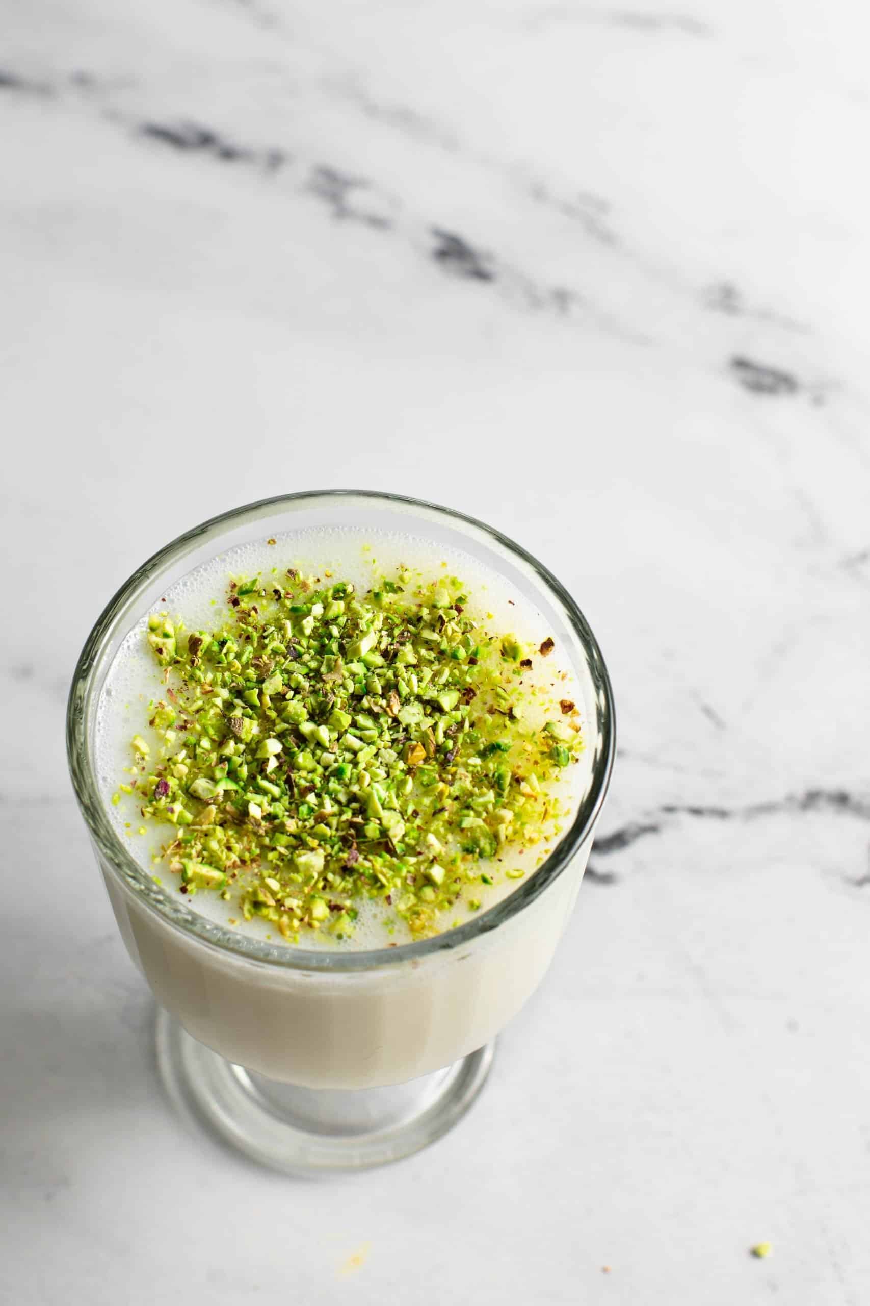 one glass filled with sahlab and topped with pistachios