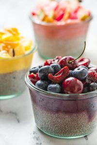 3 chia pudding in glass jar topped with pureed fruit and fresh fruit