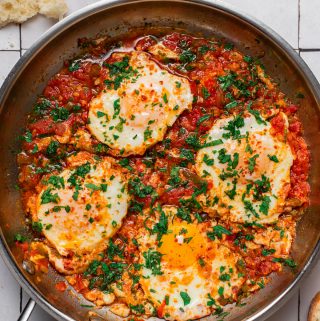 cooked shakshuka in a pan with a side of bread