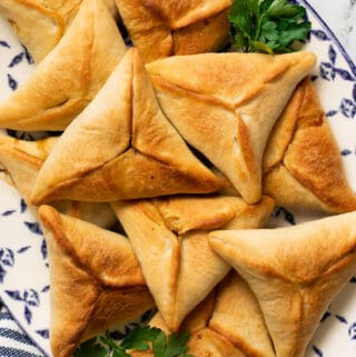 lebanese spinach pie on a decorative blue platter with a garnishes of parsley