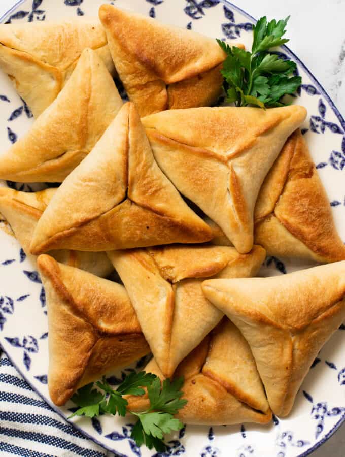 lebanese spinach pie on a decorative blue platter with a garnishes of parsley